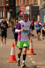 A runner running along a road wearing a CLL support tshirt