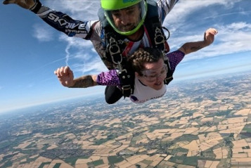 A woman attached to a skydive instructor above the earth